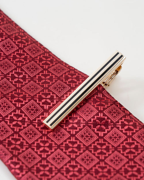 Black stripe gold-tone tie clip shown with a patterned tie