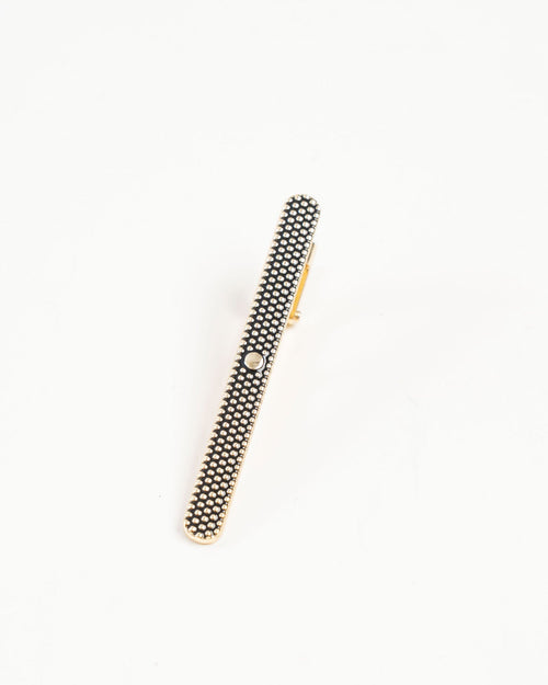 Textured black and gold-tone tie clip styled on a red patterned tie
