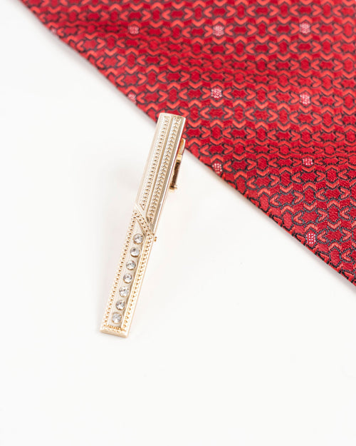 Crystal accent gold-tone tie clip detail on a red patterned tie