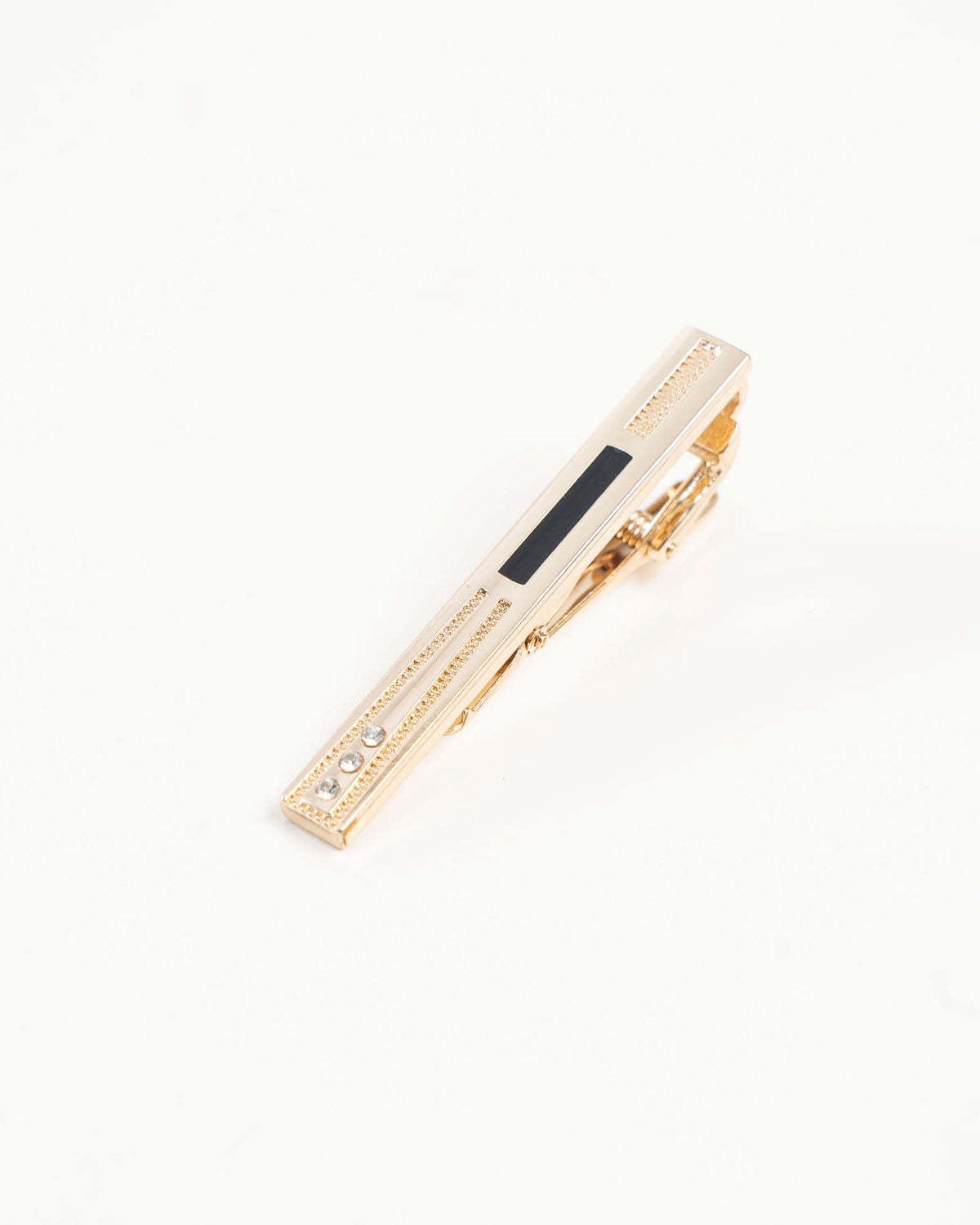 Gold-tone tie clip with black inlay and crystal accents beside a red patterned tie
